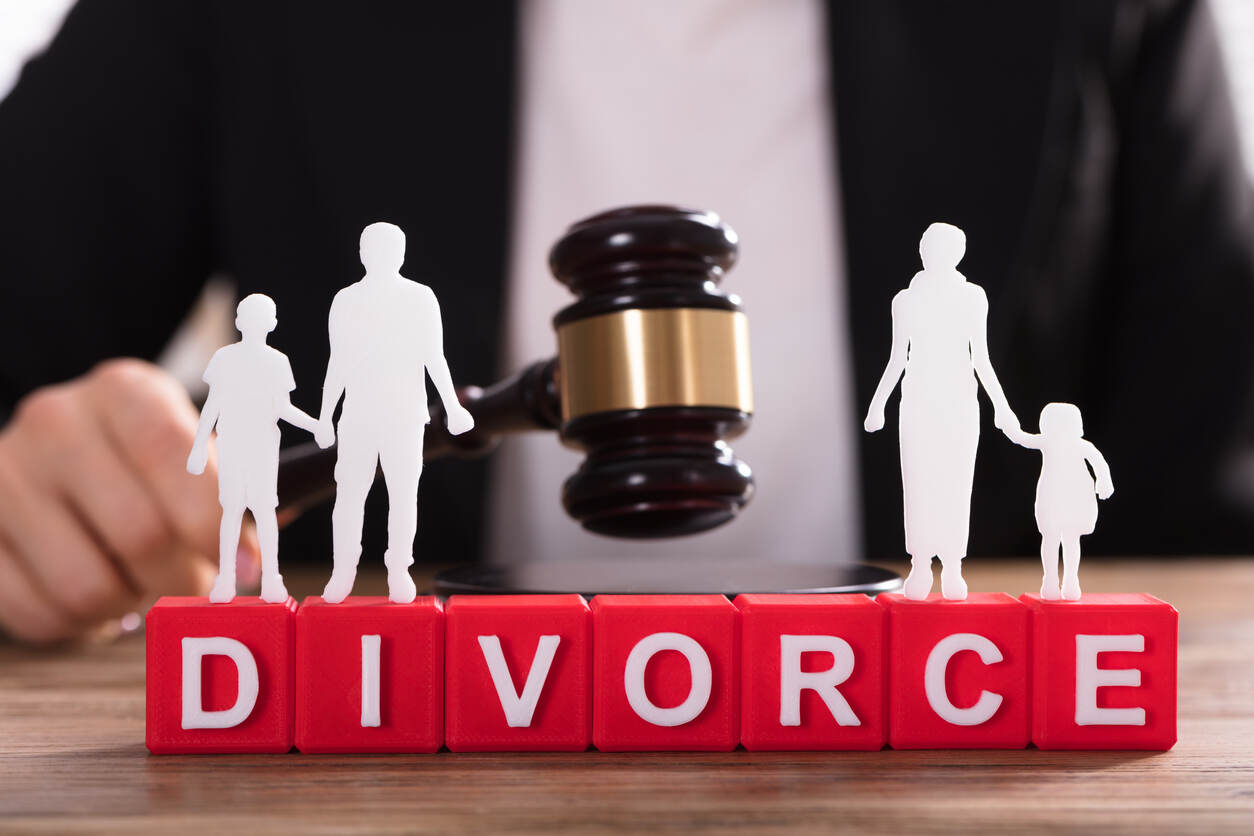 Paper cutouts of a separated family standing on 'DIVORCE' blocks with a legal gavel in the background, symbolizing the collaborative divorce process facilitated by an attorney in Stuart, Florida.