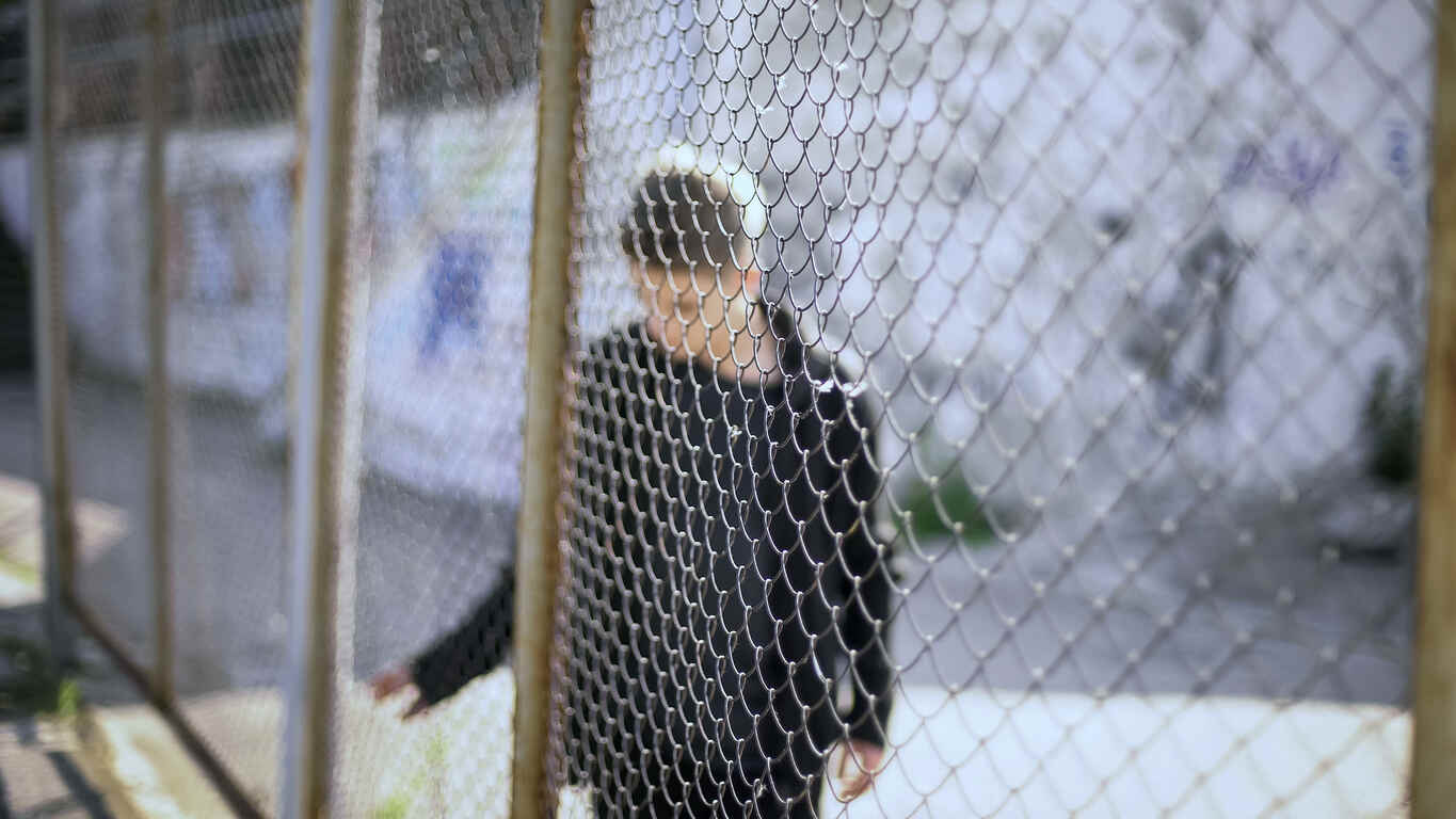 Blurred image of a young person behind a chain-link fence, symbolizing juvenile crime in Fort Pierce.