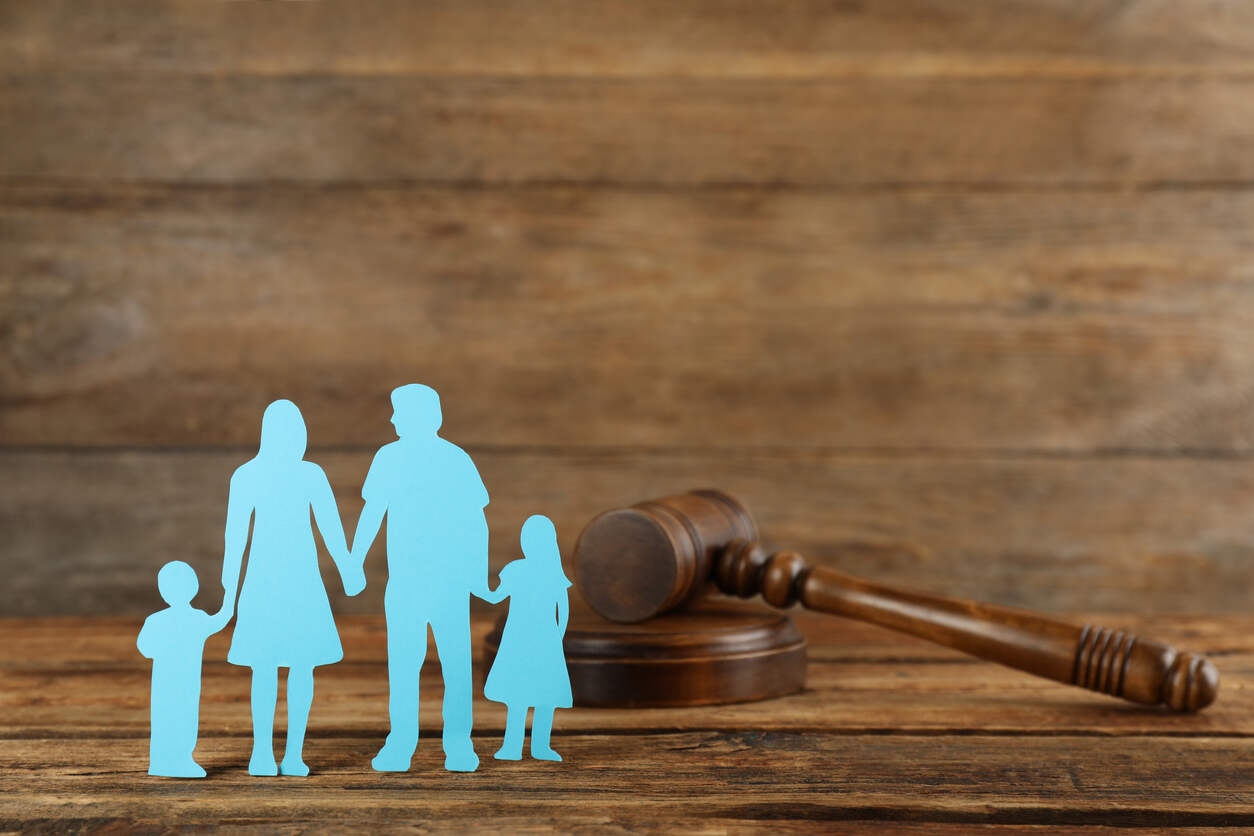Paper cutout family holding hands next to a gavel, symbolizing paternity and family law in St. Lucie County, Florida.