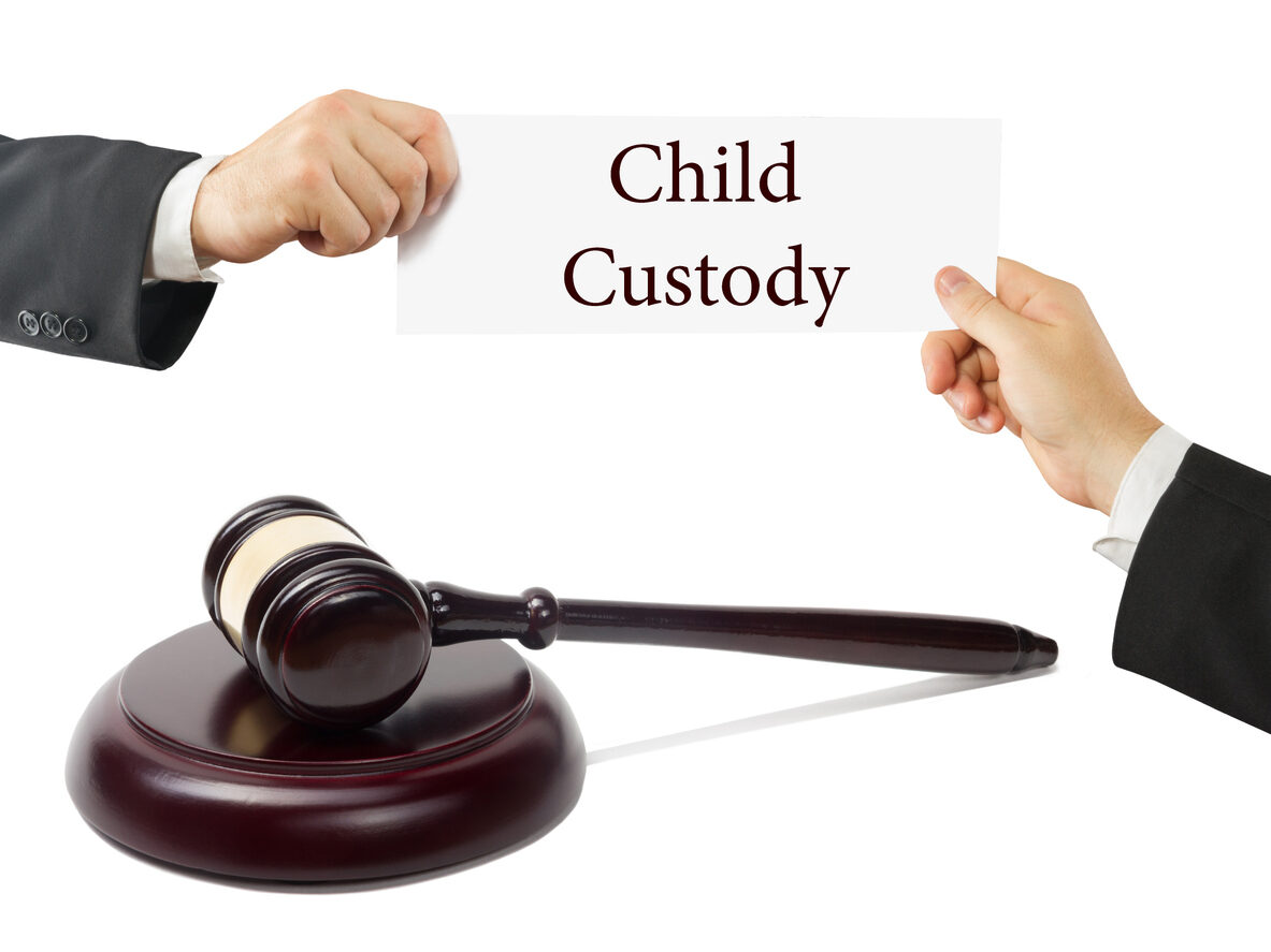 A gavel sits below two hands holding a card that says 'Child Custody,' symbolizing the legal process of deciding full custody cases in Jensen Beach.